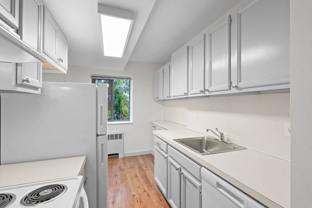 a white kitchen with white cabinets and white appliances at Vista St. Clair, Portland, 97205