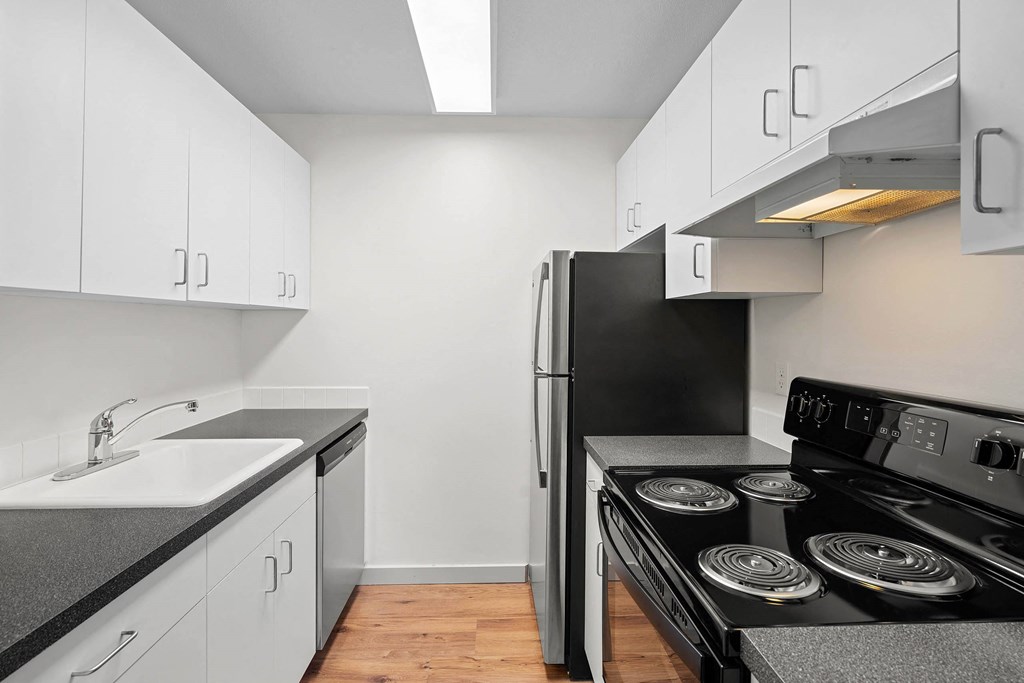 a kitchen with white cabinets and a black stove and refrigerator at Vista St. Clair, Portland, OR