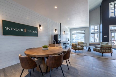 Clubhouse lounge with round wood dining table at Sonder Fields Apartments, Happy Valley, Oregon