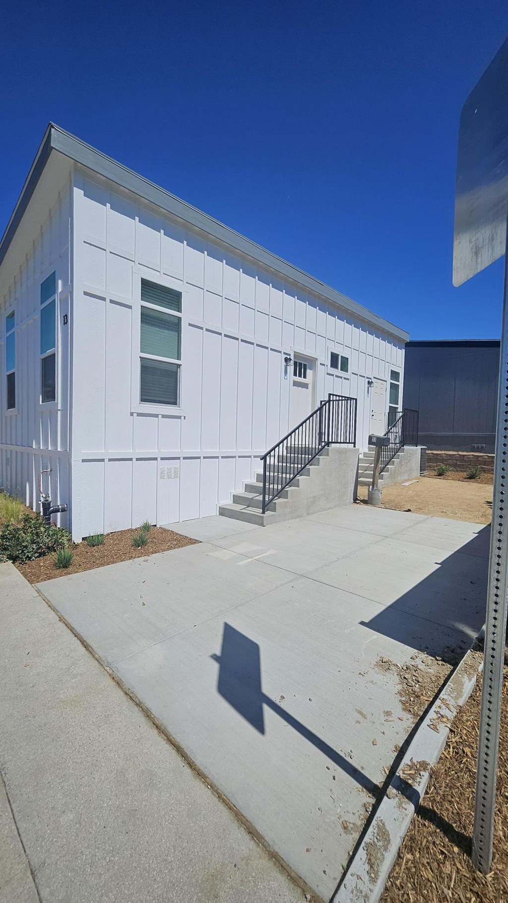 A white building with a black railing on the stairs.
