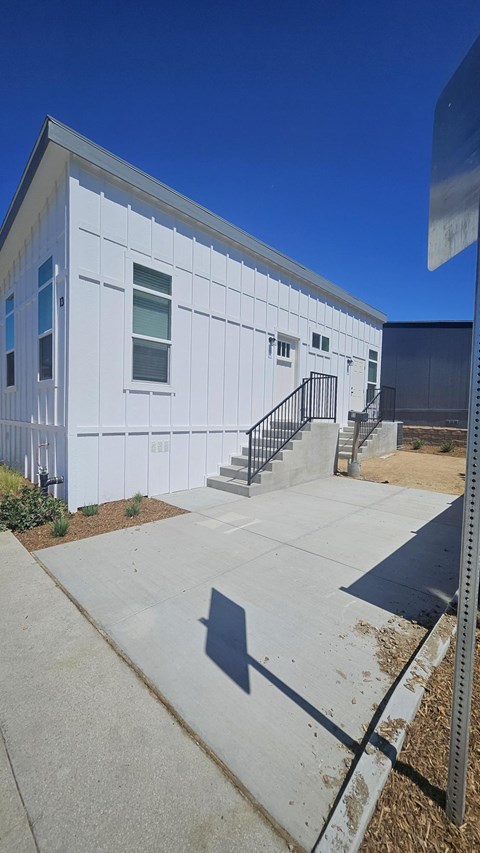 A white building with a black railing on the stairs.