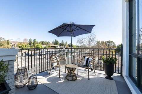 a patio with chairs and an umbrella on a balcony