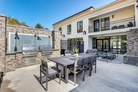 a patio with a dining table and a barbecue grill