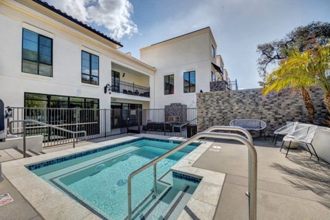 a resort style pool with chairs and a building in the background