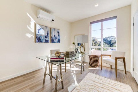 a living room with a glass desk and a window