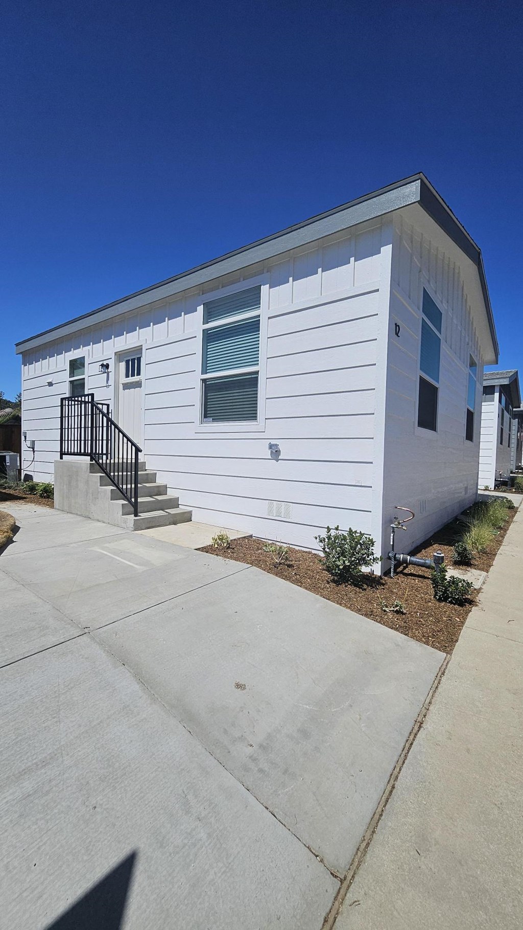 A white house with a black railing on the stairs.
