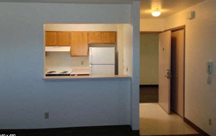 an empty kitchen with a refrigerator and a door
