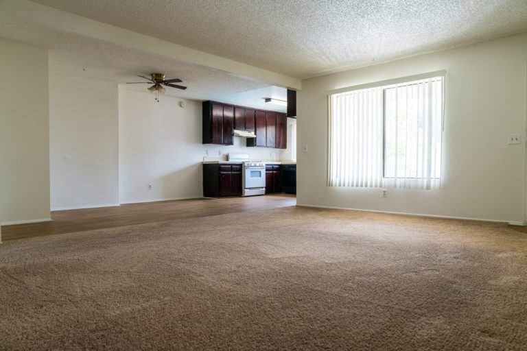 an empty living room and kitchen with a ceiling fan