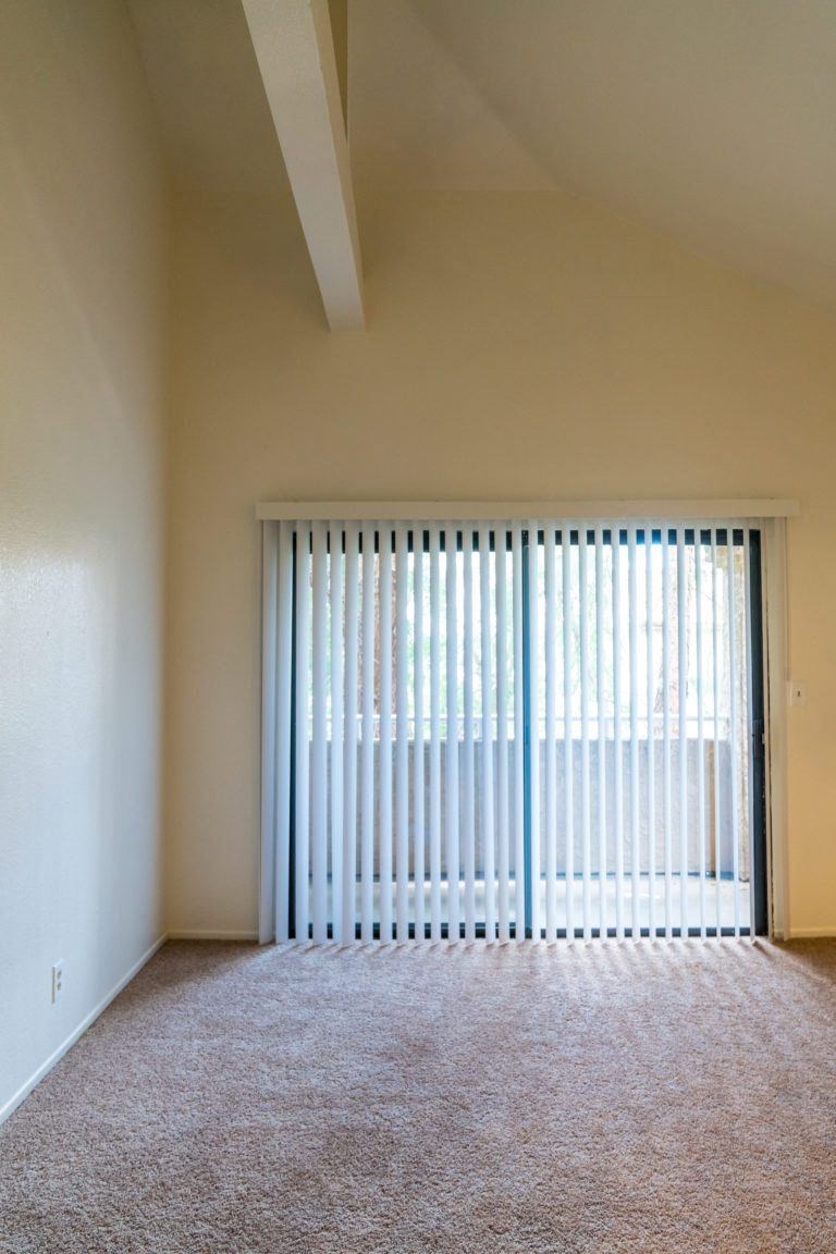 an empty living room with a window and blinds
