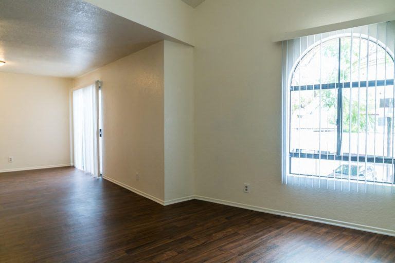 an empty living room with a large window and wooden floors