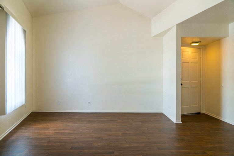 an empty living room with wood flooring and a door