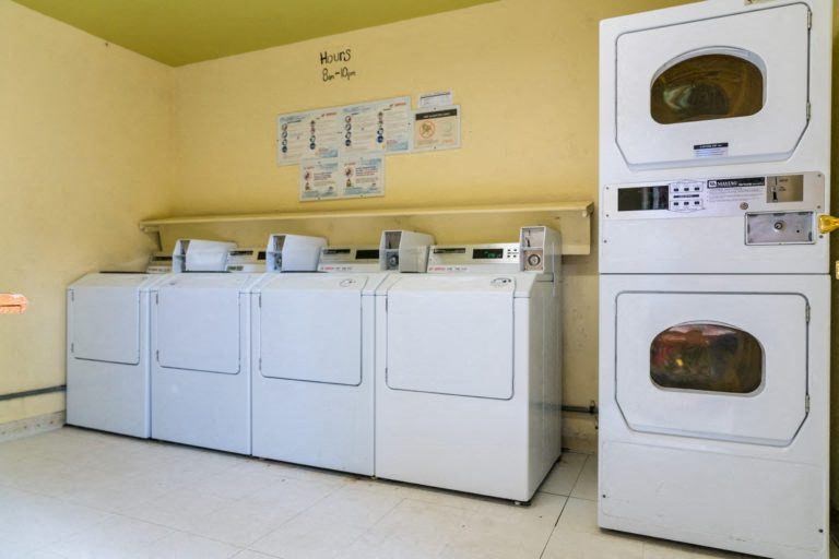 a row of washes and dryers in a laundry room