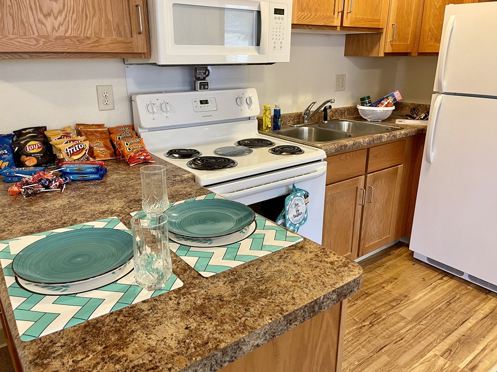 a kitchen with a stove sink and microwave and a counter with plates on it