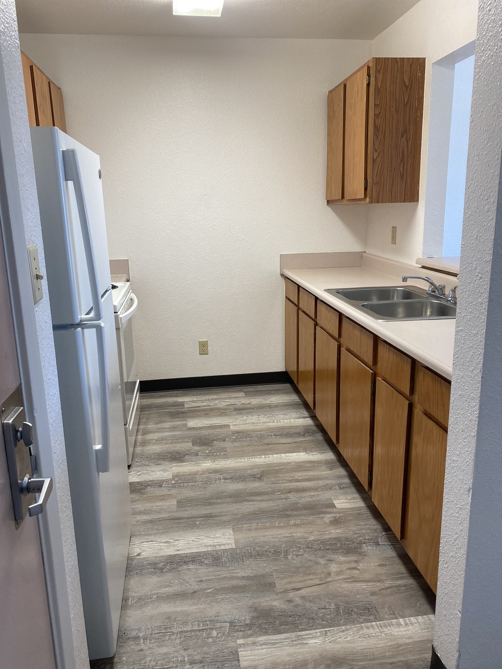 an empty kitchen with a refrigerator and sink