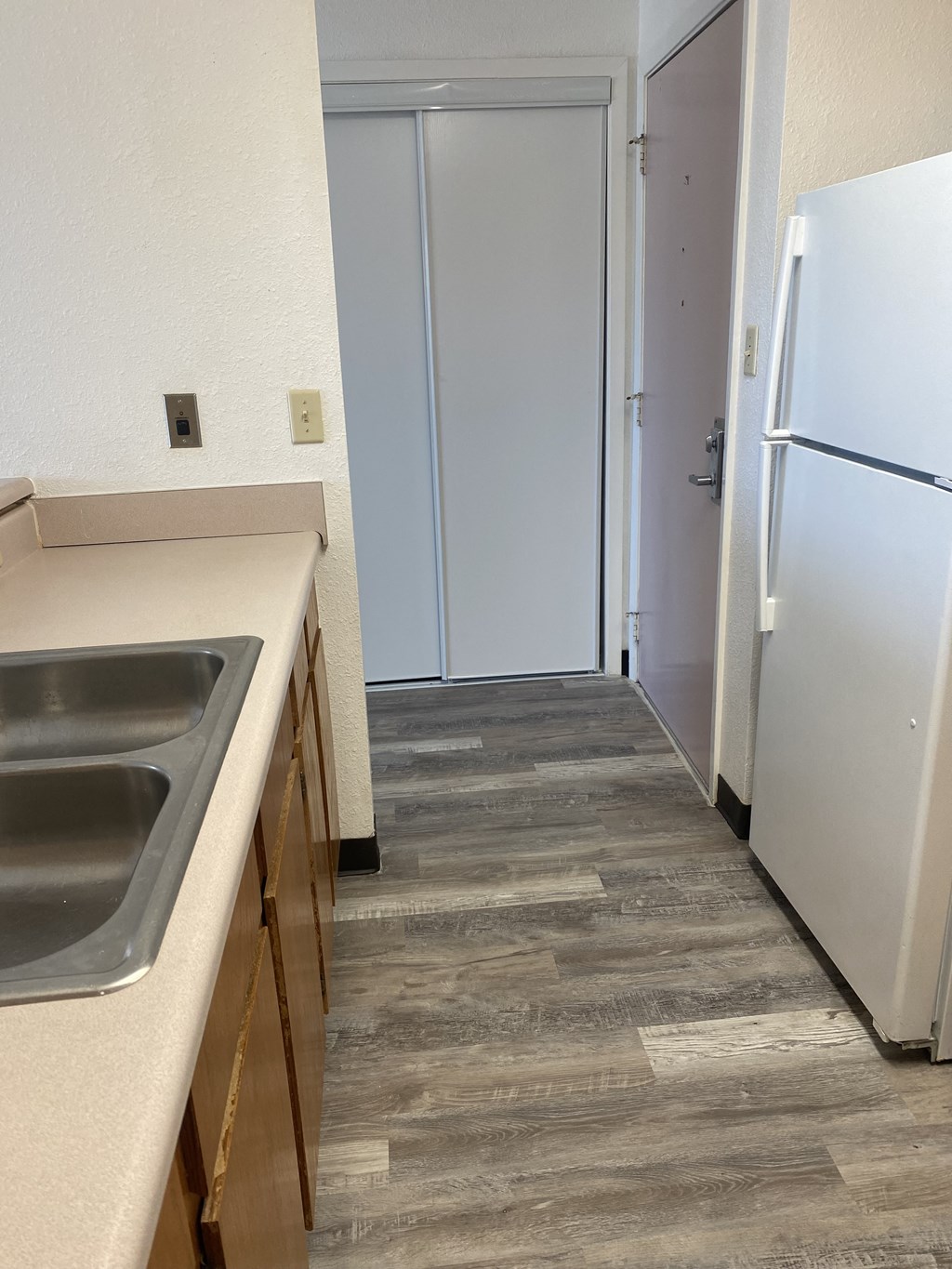 an empty kitchen with a sink and a refrigerator
