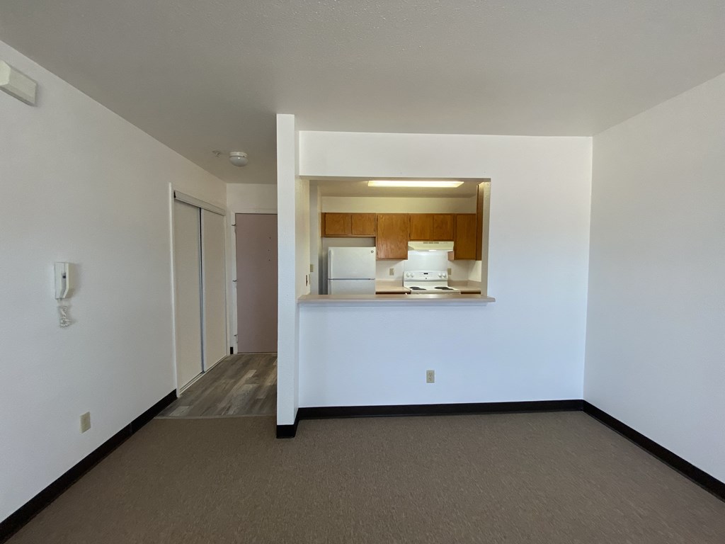 the living room and kitchen of an empty apartment with white walls