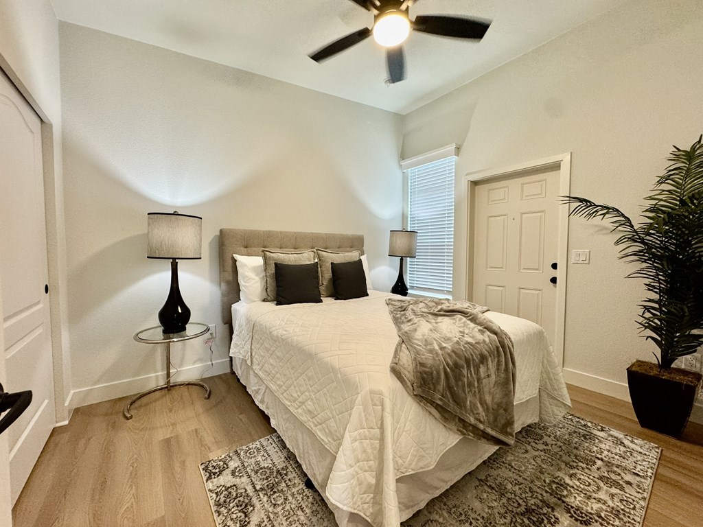 A bedroom with a bed, two lamps, and a ceiling fan.