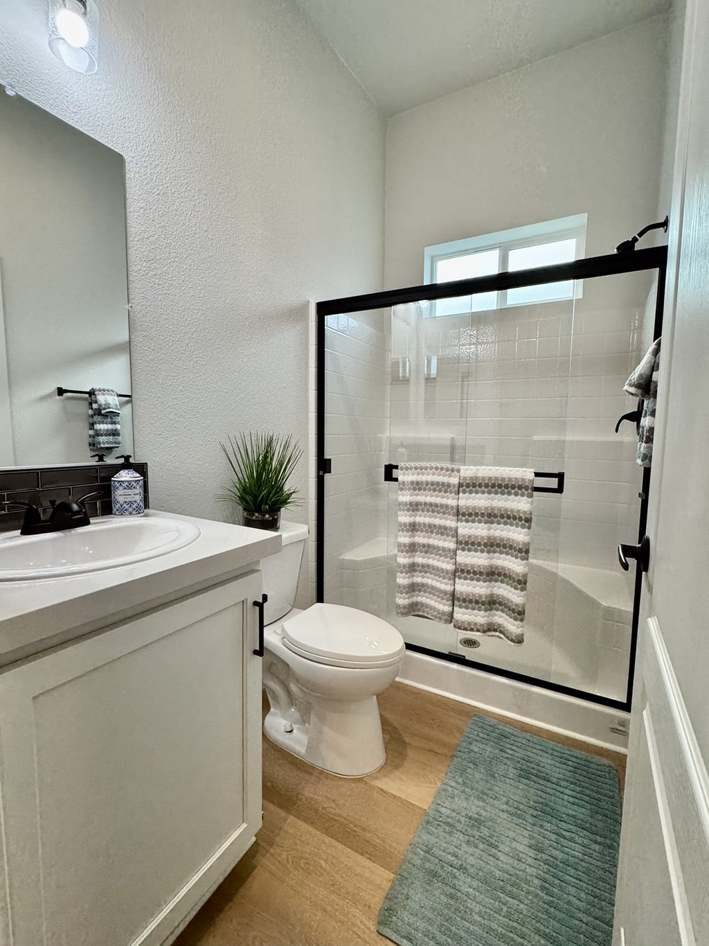 A white toilet sits in a bathroom next to a sink and a glass shower door.