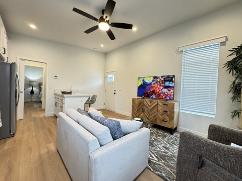 A living room with a grey couch and a ceiling fan.