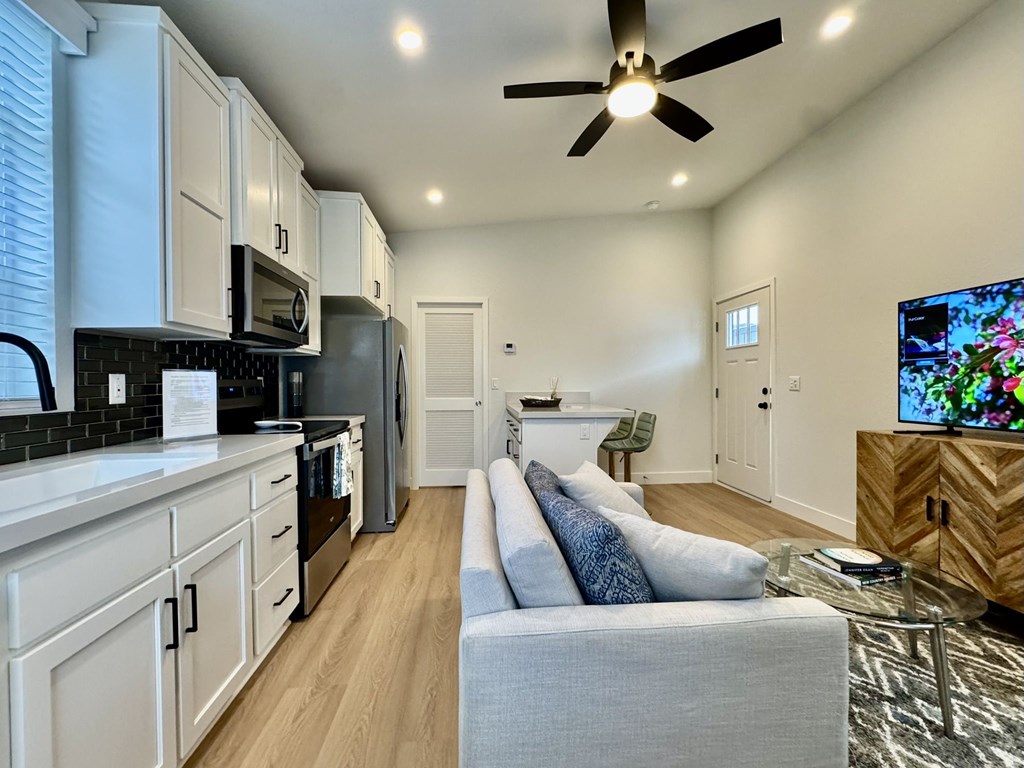 A modern kitchen with a grey couch and a ceiling fan.