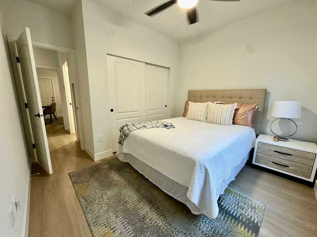 A bedroom with a bed, nightstand, and rug.