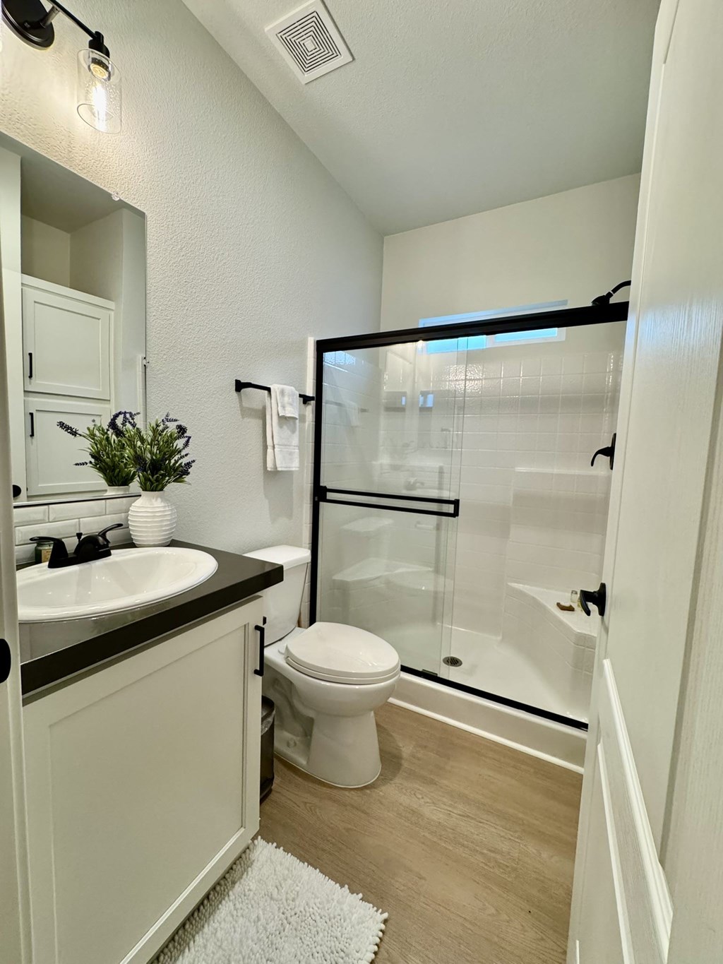 A white toilet is in a bathroom with a black counter top.