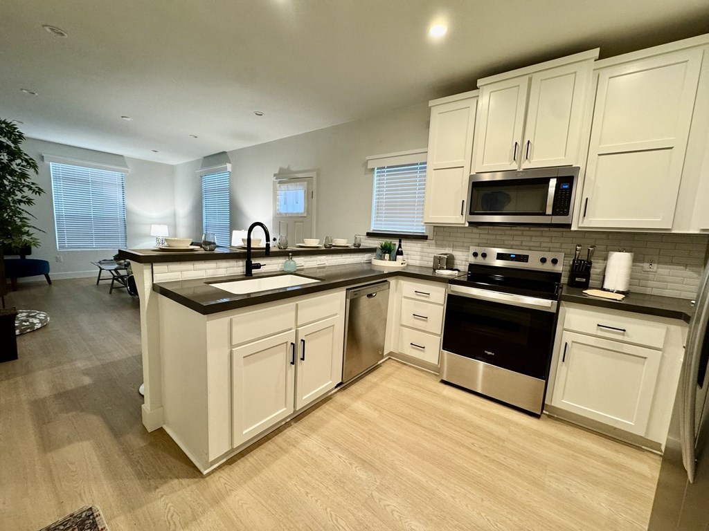 A kitchen with white cabinets and wooden floors.