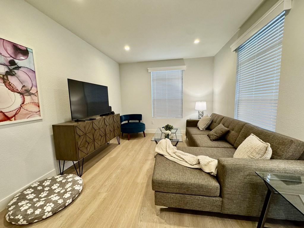 A living room with a brown couch, a television, and a glass coffee table.