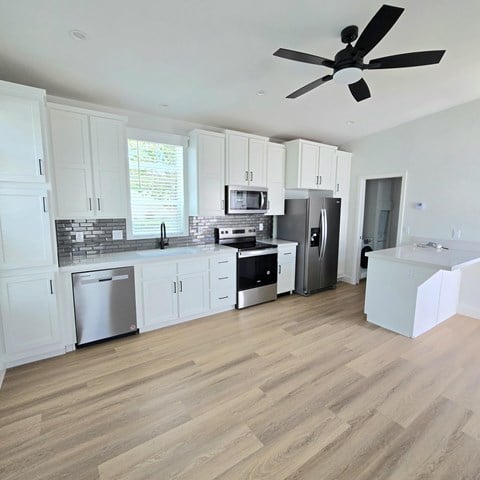 A kitchen with white cabinets and a wooden floor.