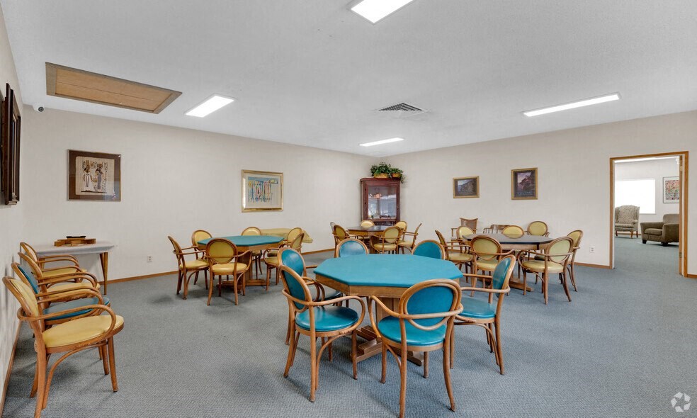 a community room with tables and chairs and a fireplace