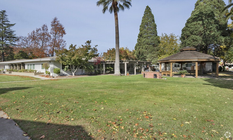 a gazebo in the middle of a grassy field in a park