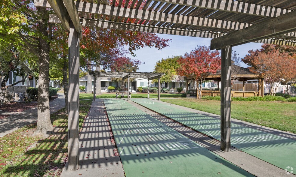 a green pathway with trees and houses in the background