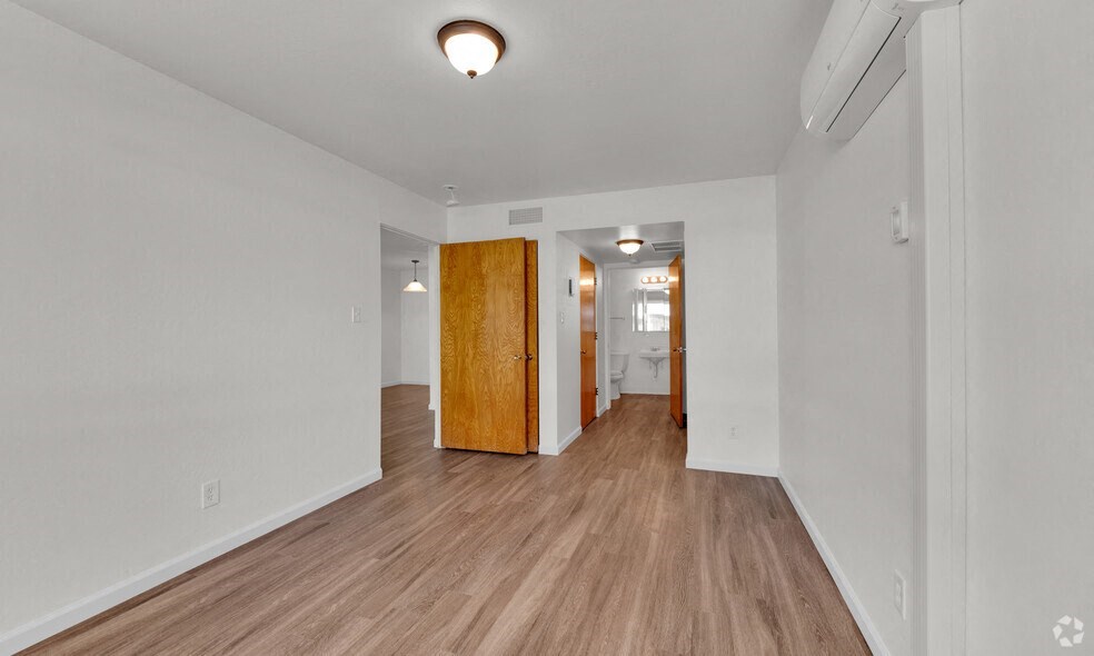 the living room and dining room of an apartment with wood floors and white walls