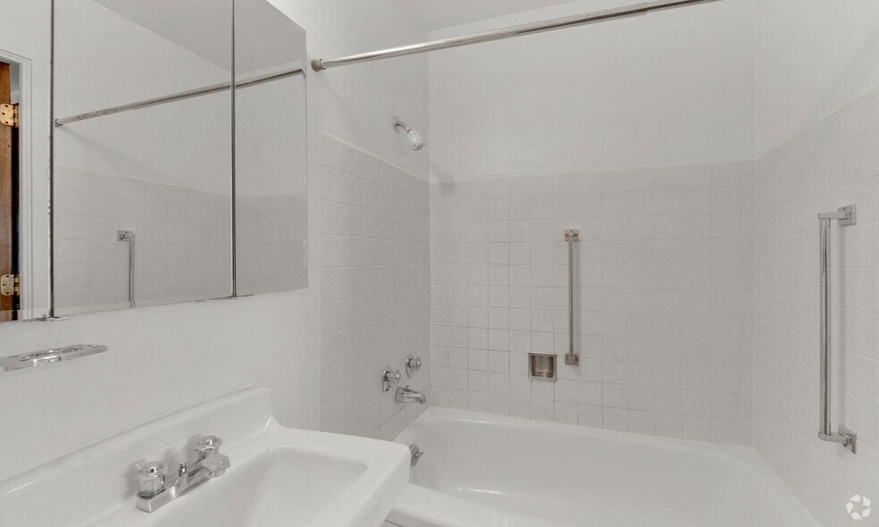 a white bathroom with a tub and a sink and a mirror