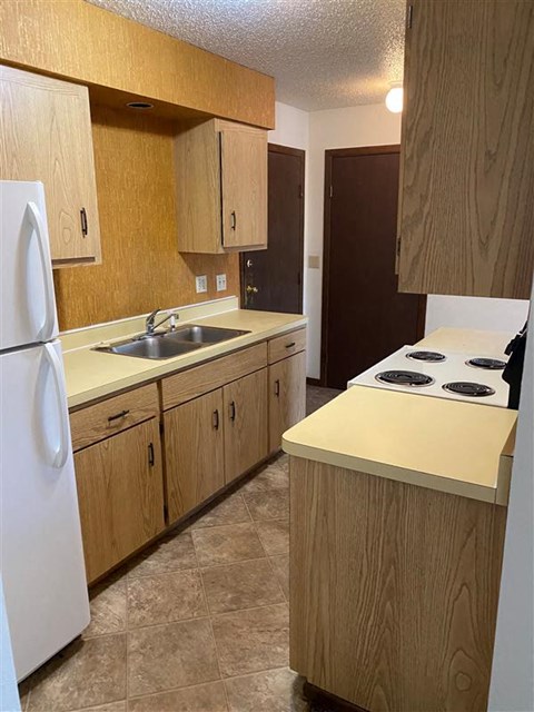 A kitchen with wooden cabinets and a white refrigerator.