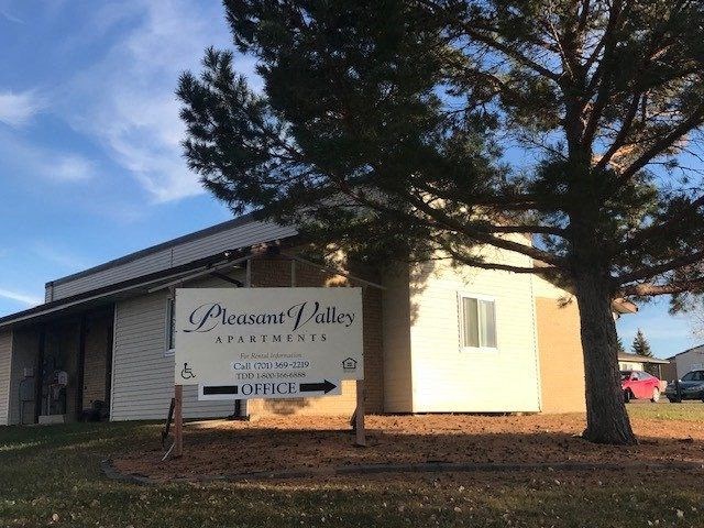 A sign for Pleasant Valley Apartments is in front of a building.