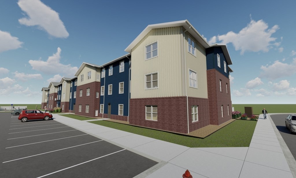 A red car is parked in a parking lot in front of a building.