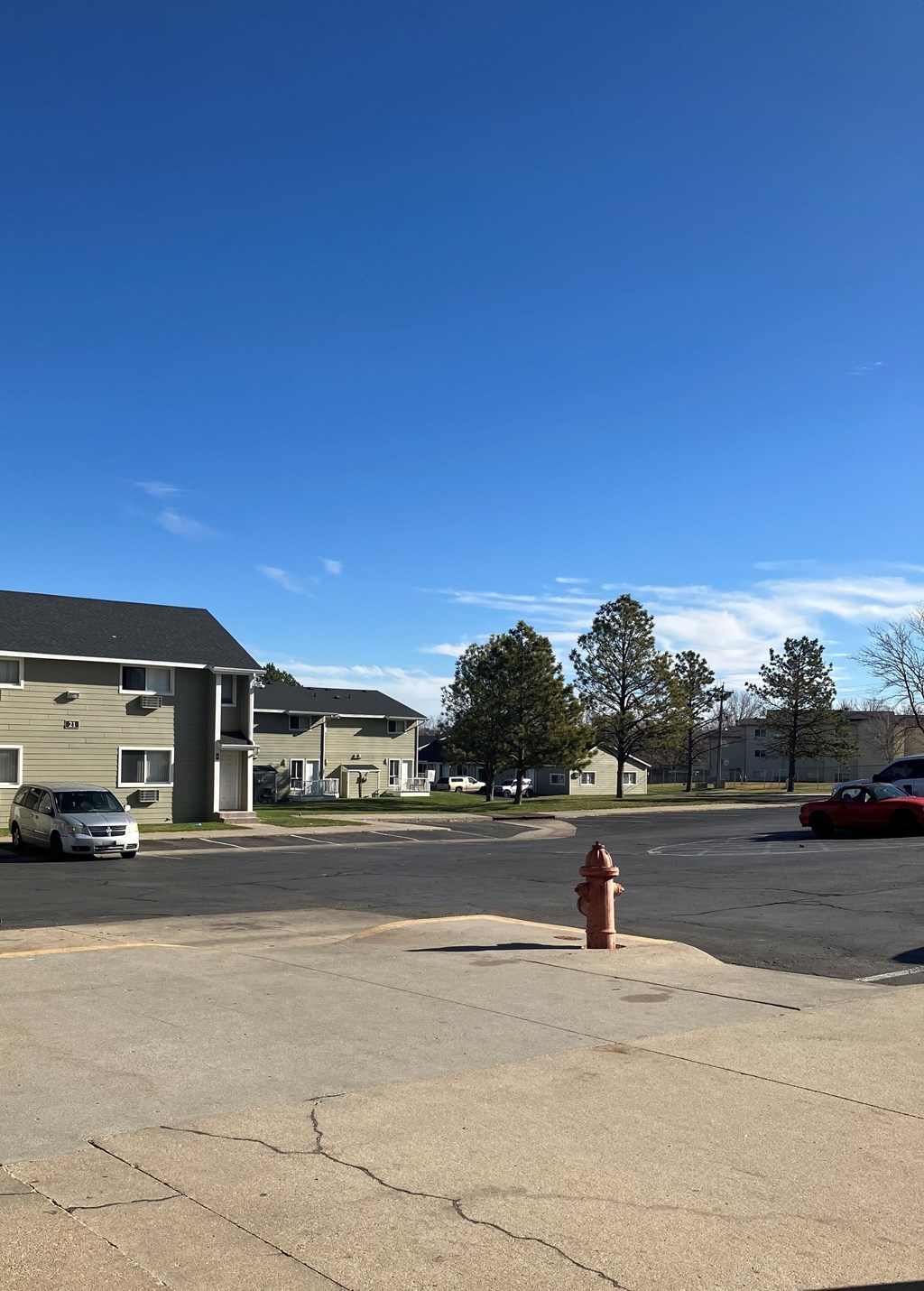 A red fire hydrant sits in the middle of a parking lot.
