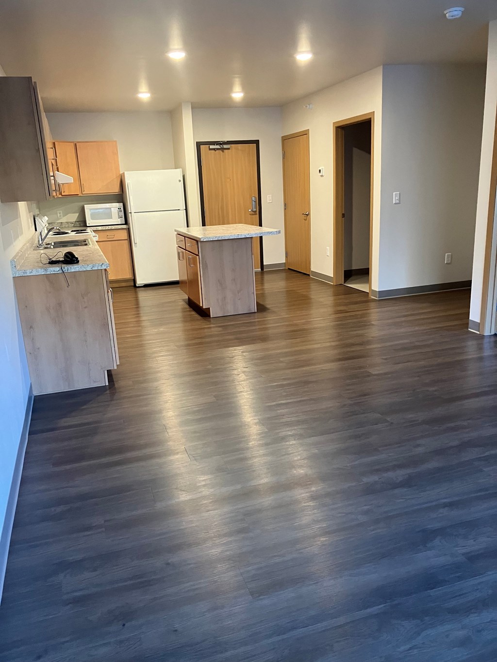 A kitchen with a refrigerator, microwave, and oven.