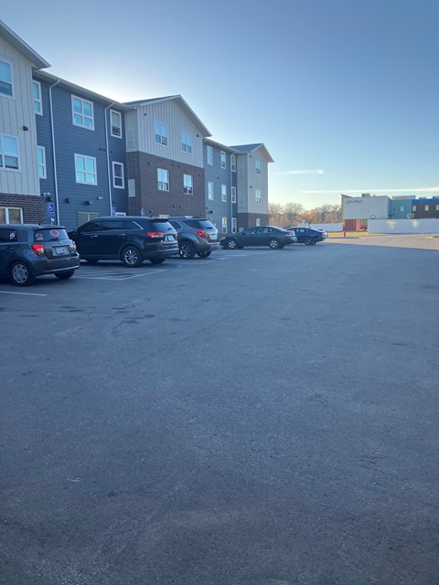 A parking lot with several cars and apartment buildings in the background.