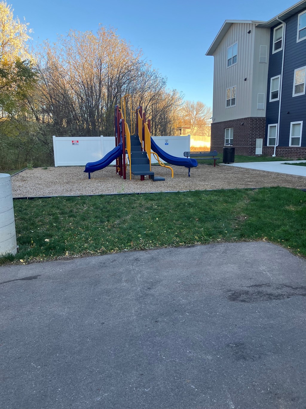 A playground with a slide and a bench in front of a building.