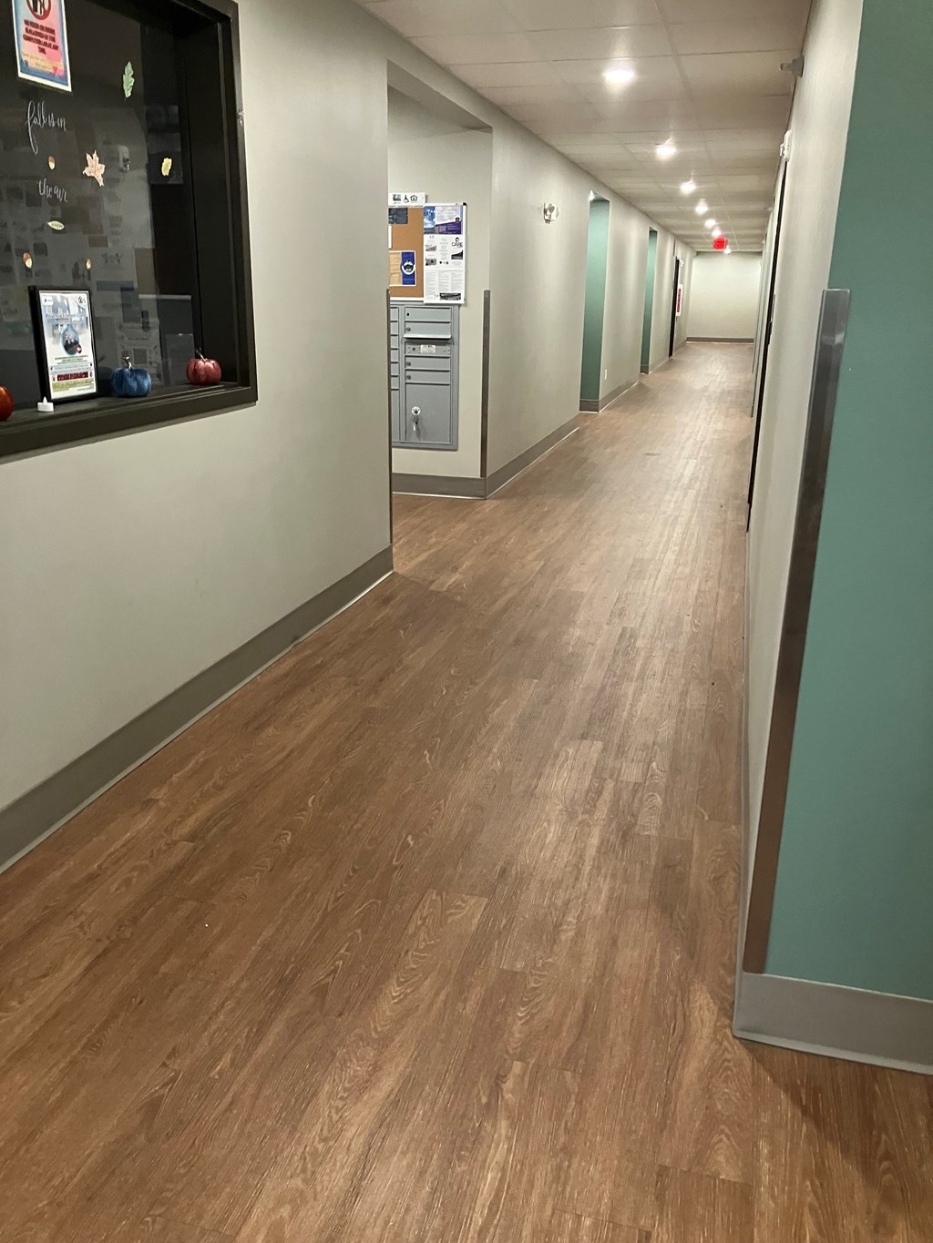 A long hallway with wood floors and white walls.