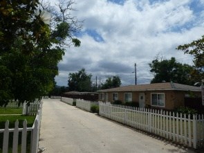 a house with a white fence and a road in front of it