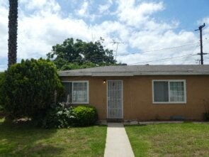 a small brown house with a sidewalk in front of it