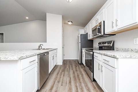 A kitchen with white cabinets and a marble countertop.