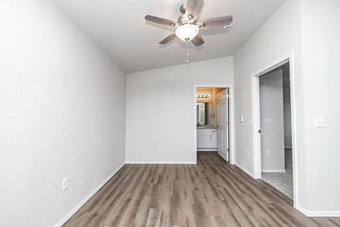 A room with a ceiling fan and wooden flooring.