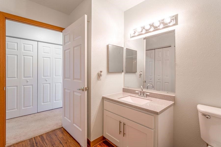A white bathroom with a sink, mirror, and a white tub.