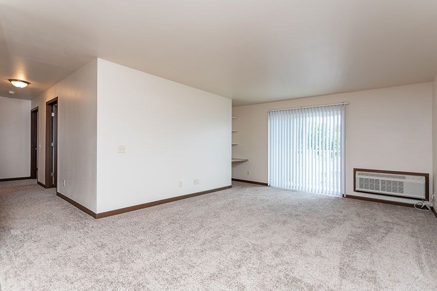 A sparsely furnished room with a window covered by blinds.