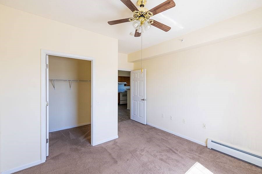 A room with a ceiling fan and a carpeted floor.