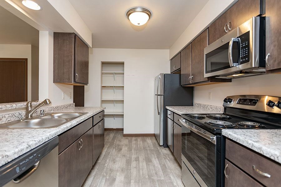 A kitchen with a stove, sink, and refrigerator.
